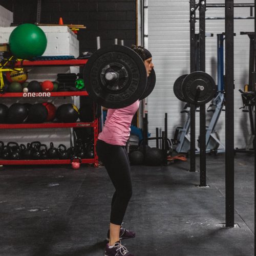 Woman with weight on her shoulders getting ready to do squats in a gym