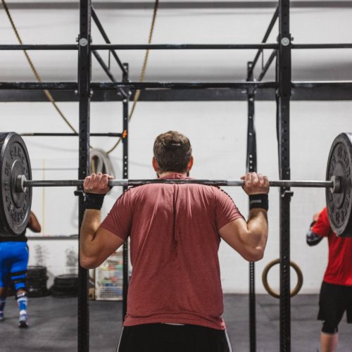 Man with a bar on his shoulders getting ready to do squats in a gym